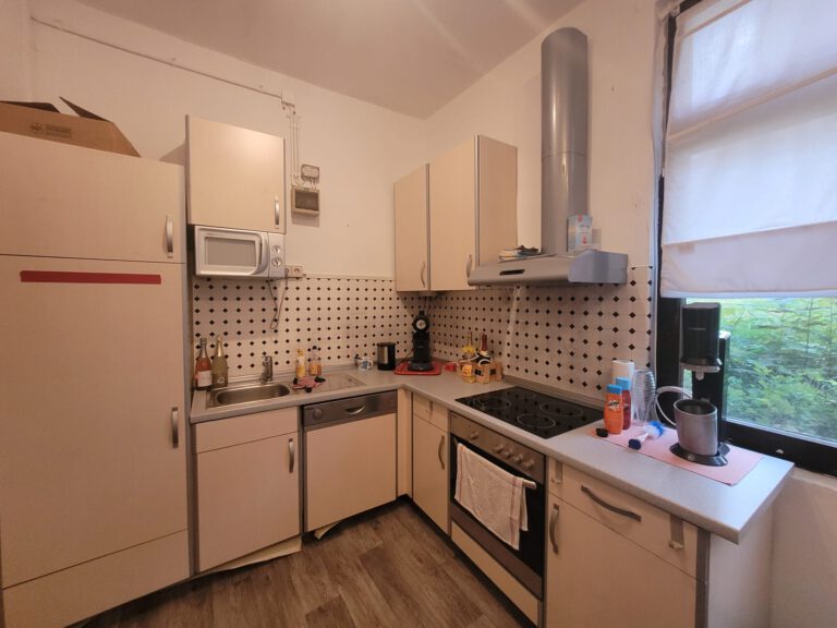 Moderne Küche mit hellen Holzschränken, Einbaugeräten und gepunkteter Küchenrückwand. Fenster auf der rechten Seite mit Aussicht, perfekt für alle, die eine stilvolle Startseite durchstöbern.